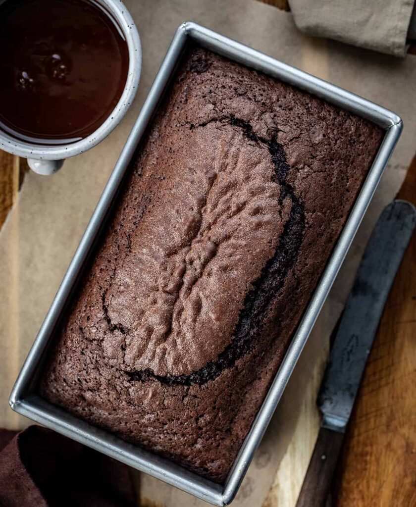 Brownie-Brot ist ein Laib schokoladenweiches Brot, das wie ein Brownie schmeckt, aber wie eine Scheibe Brot geschnitten und serviert wird. Milchschokoladen-Ganache verleiht dem Brot noch mehr Schokoladengeschmack! Es ist ein schnell gebackenes Brot, das garantiert schnell verputzt ist! Dieser köstliche Leckerbissen oder Nachtisch wird Ihre Naschsucht und Ihren Schokoladenhunger stillen.